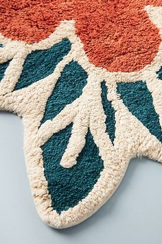 an orange and blue rug on top of a white table with a cat laying next to it