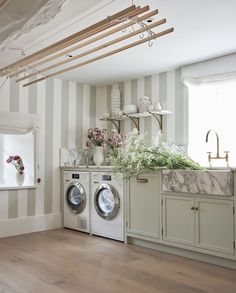 a washer and dryer sitting in a room next to a window with striped walls