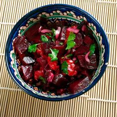 a bowl filled with beets and cilantro on top of a mat