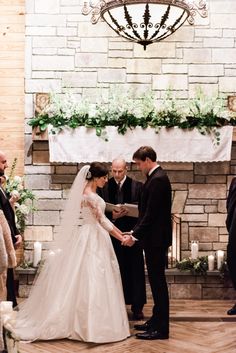 a bride and groom are getting married in front of the fireplace at their wedding ceremony