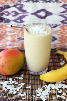 there is a smoothie in a glass next to two bananas and an apple on the table