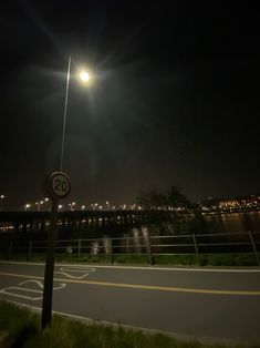 a street sign sitting on the side of a road under a full moon lit sky