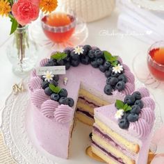 a cake with blueberries and flowers on it is cut in half to show the layers