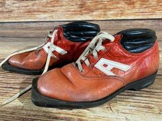 an old pair of red and black shoes sitting on top of a wooden floor