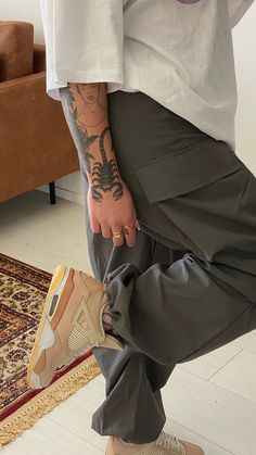 a man with tattoos on his arm and leg holding onto a pair of nike air jordans