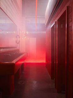 an empty room with red light coming from the ceiling and some lockers in it