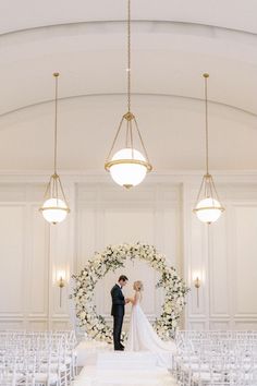 a bride and groom standing at the end of their wedding ceremony in front of an archway decorated with white flowers