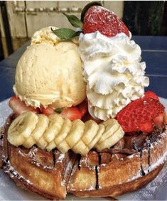 a waffle topped with bananas, strawberries and ice cream