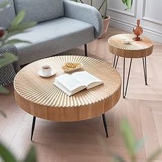 two coffee tables sitting on top of a hard wood floor next to a gray couch