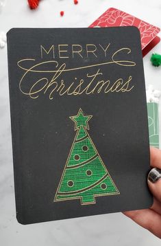 someone holding up a christmas card with a tree on it