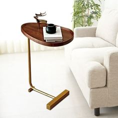 a table with a cup on it next to a white couch and potted plant