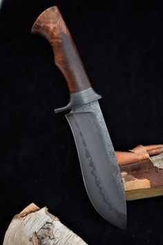 a large knife sitting on top of a piece of wood