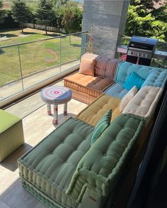 the couches are lined up on the balcony overlooking the yard and patio area with an outdoor grill