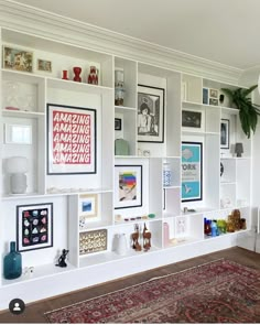 a living room filled with lots of white shelves and pictures on the wall above it