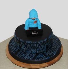 a cake with a blue figure sitting on top of it's head and laptop