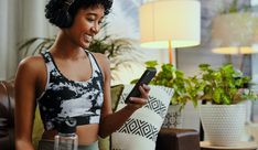 a woman wearing headphones is looking at her cell phone while sitting on the couch