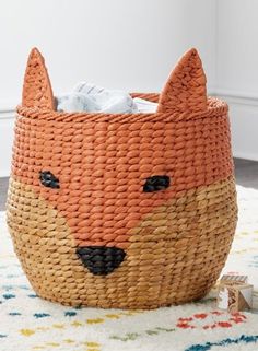 a woven basket with a fox face on the inside is sitting on top of a rug