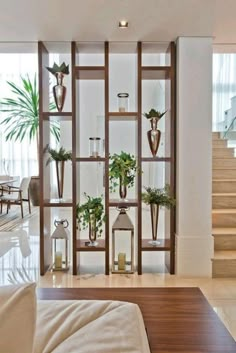 a living room filled with lots of furniture next to a stair case covered in potted plants