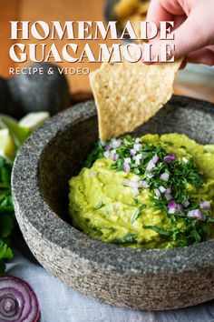 a person dipping guacamole into a bowl with tortilla chips on the side