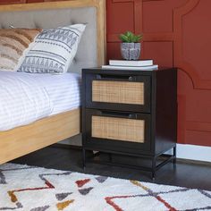 a bed with two drawers and a white blanket on top of it next to a red wall