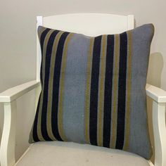 a striped pillow sitting on top of a white chair next to a wooden armrest