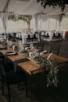 tables set up for an event with white linens and greenery on the table