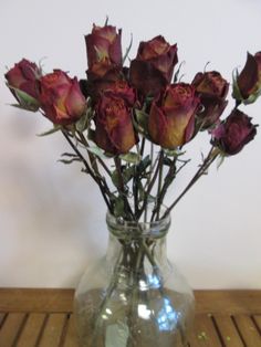 a vase filled with red roses on top of a wooden table