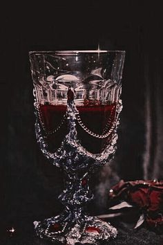 a glass filled with red liquid sitting on top of a black table next to a cloth