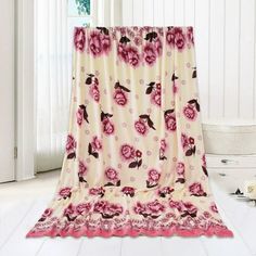 a pink flowered blanket sitting on top of a white floor next to a window