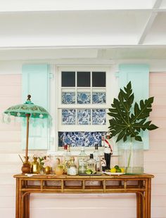 a wooden table topped with lots of bottles next to a window