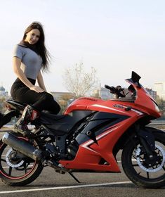 a woman sitting on top of a red motorcycle