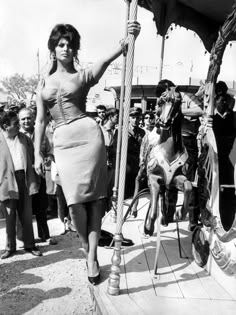 an old photo of a woman on a merry go round with horses and men in the background