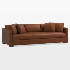 a brown leather couch with four pillows on the back and one arm folded up to show the