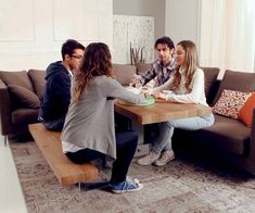 four people sitting around a table in a living room