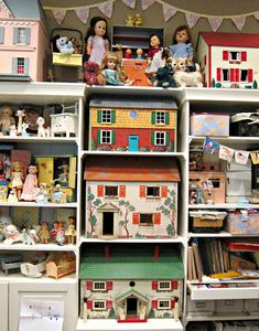 many dolls are on top of shelves in a room