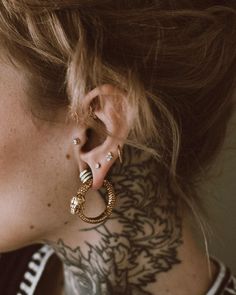 a close up of a person with tattoos on their neck and behind them is an ear ring