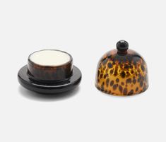 a brown and black container sitting on top of a white table next to a candle holder