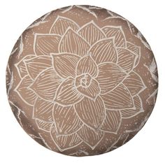 a brown and white flower design on a round pillow