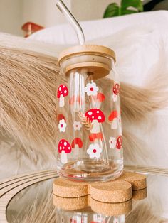 a glass jar filled with red and white flowers on top of a wooden coaster next to a bed