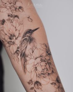 a woman's arm with flowers and a bird on the back of her arm