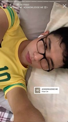 a young man laying in bed wearing glasses