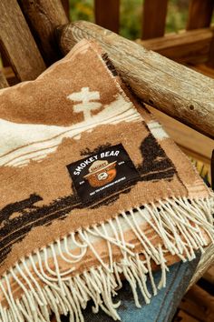 a brown and white blanket sitting on top of a wooden chair next to a remote control