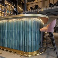 the bar is decorated in blue and gold with barstools on each side, along with pink velvet stools