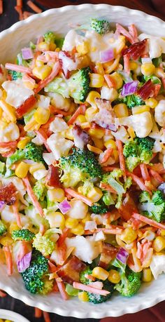 a bowl filled with corn, broccoli and other vegetables on top of a table