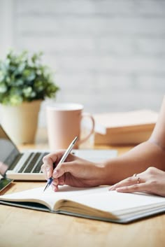 two people sitting at a table with laptops and notebooks in front of them