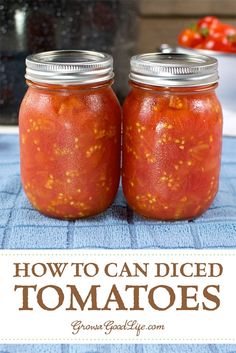 two jars filled with tomato sauce sitting on top of a blue towel next to tomatoes