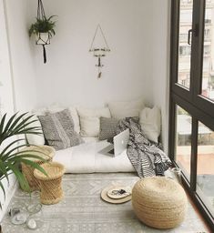 a living room filled with lots of white furniture and plants on top of a wooden floor