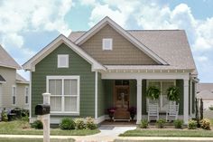 a green house with white trim and two porches