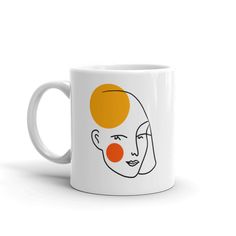 a white coffee mug with an orange face on it