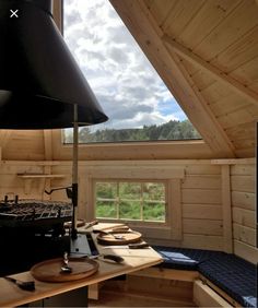 a stove top oven sitting under a window in a wooden room next to a table